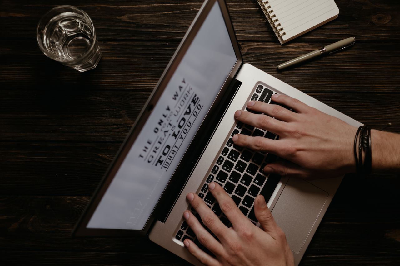 Hands on a laptop with an inspirational quote displayed on the screen, shot from above.